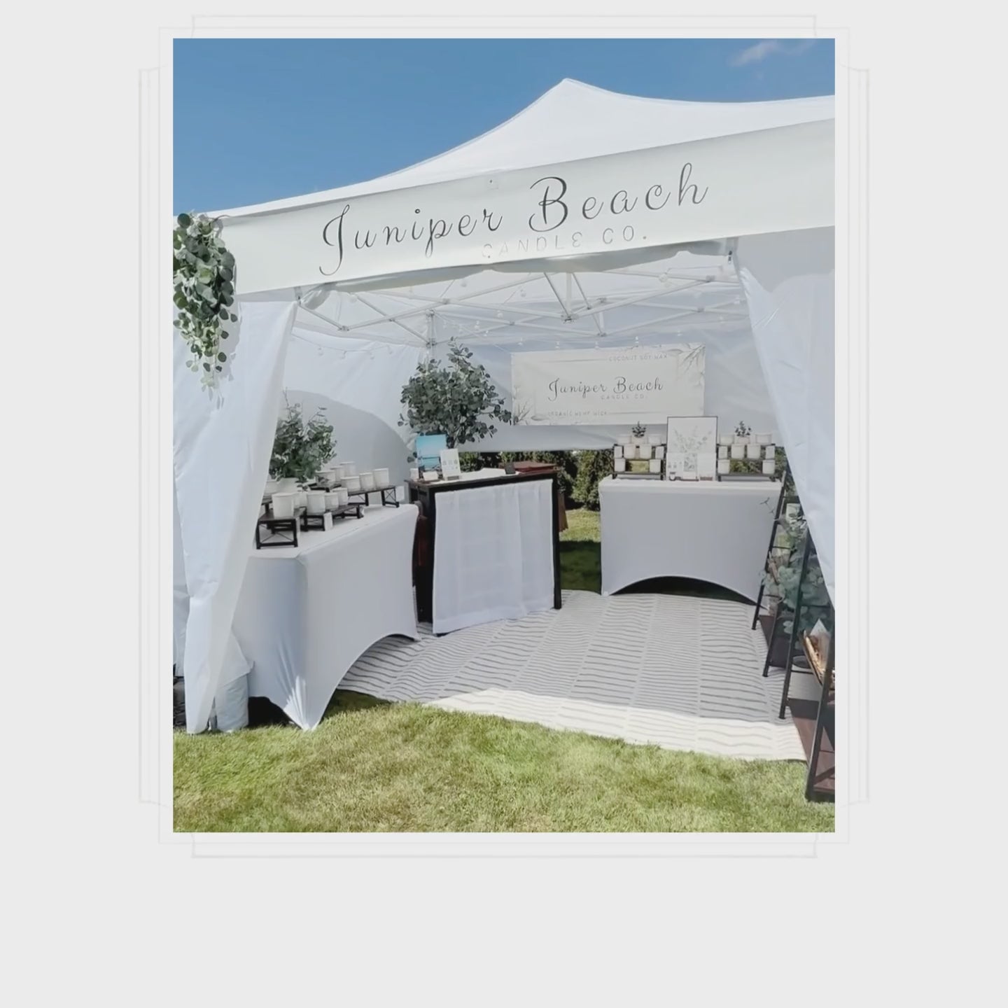 Juniper Beach Candle Co. candle display inside a white market booth at a local outdoor event